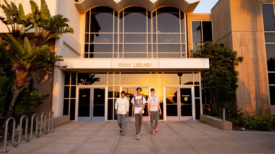 ryan library with three students standing in front
